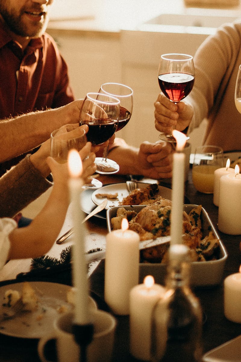 Three pairs of hands meeting over a candlelit table at the end of an evening.